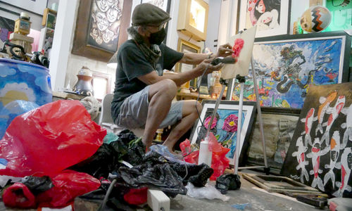 Dwiyono (66) melukis dengan memanfaatkan limbah sampah plastik di workshop galery miliknya di kawasan Rawamangun, Jakarta Timur, Kamis, 6 Januari 2022. Foto: Ismail Pohan/TrenAsia