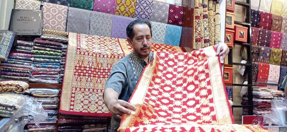 Pedagang menunjukan songket Palembang 