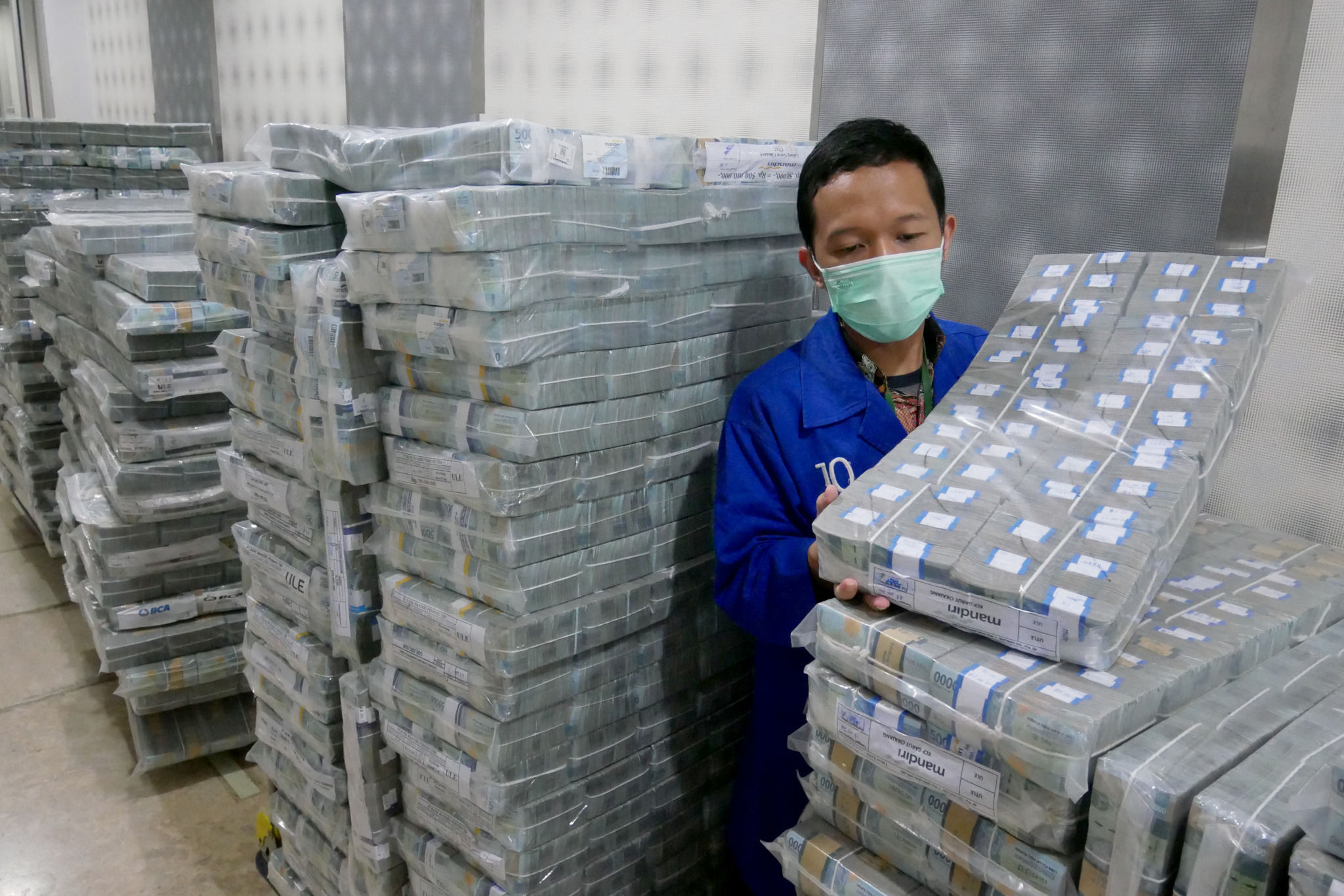 Karyawan memindahkan tumpukan uang rupiah di cash pooling Bank Mandiri, Jakarta, Jum'at, 21 Januari 2022. Foto: Ismail Pohan/TrenAsia