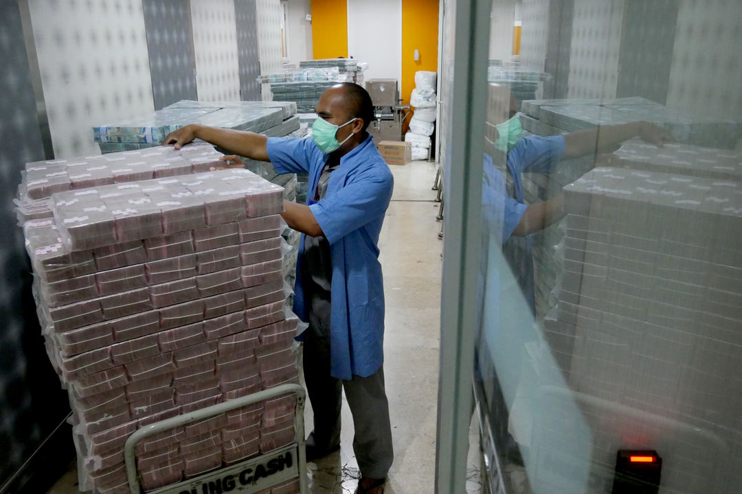 Karyawan memindahkan tumpukan uang rupiah di cash pooling Bank Mandiri, Jakarta, Jum'at, 21 Januari 2022. Foto: Ismail Pohan/TrenAsia