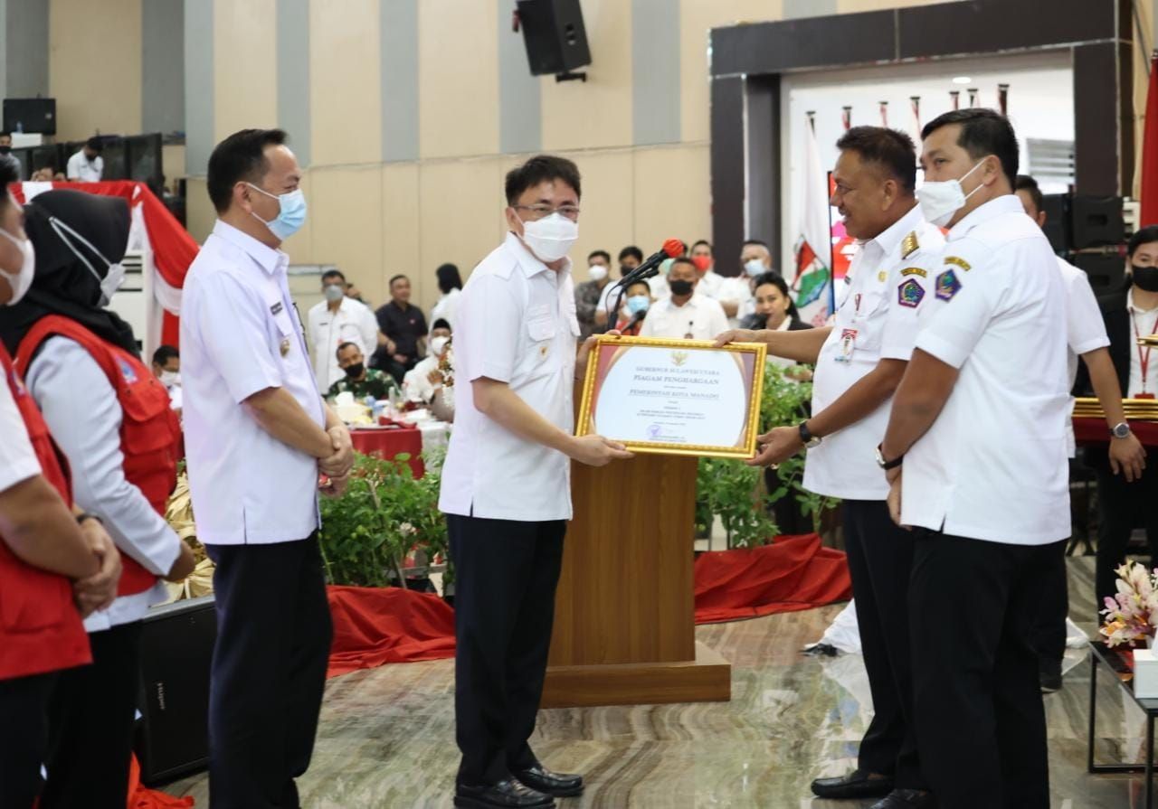 Wali Kota Manado Andrei Angouw saat menerima penghargaan dari Gubernur Sulut, Olly Dondokambey. (Foto:Istimewa)