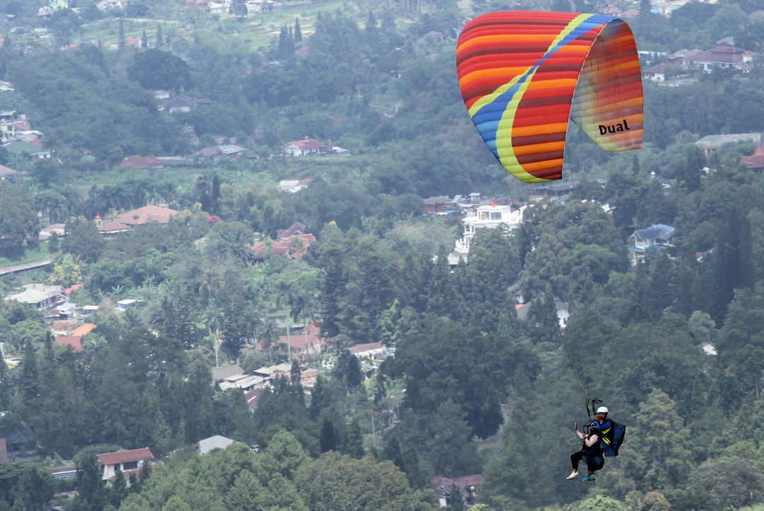 Para penggemar olahraga sekaligus wisata paralayang tengah melakukan penerbangan di kawasan Gunung Mas Puncak Bogor,Minggu 7 Februari 2022. Foto : Panji Asmoro/TrenAsia