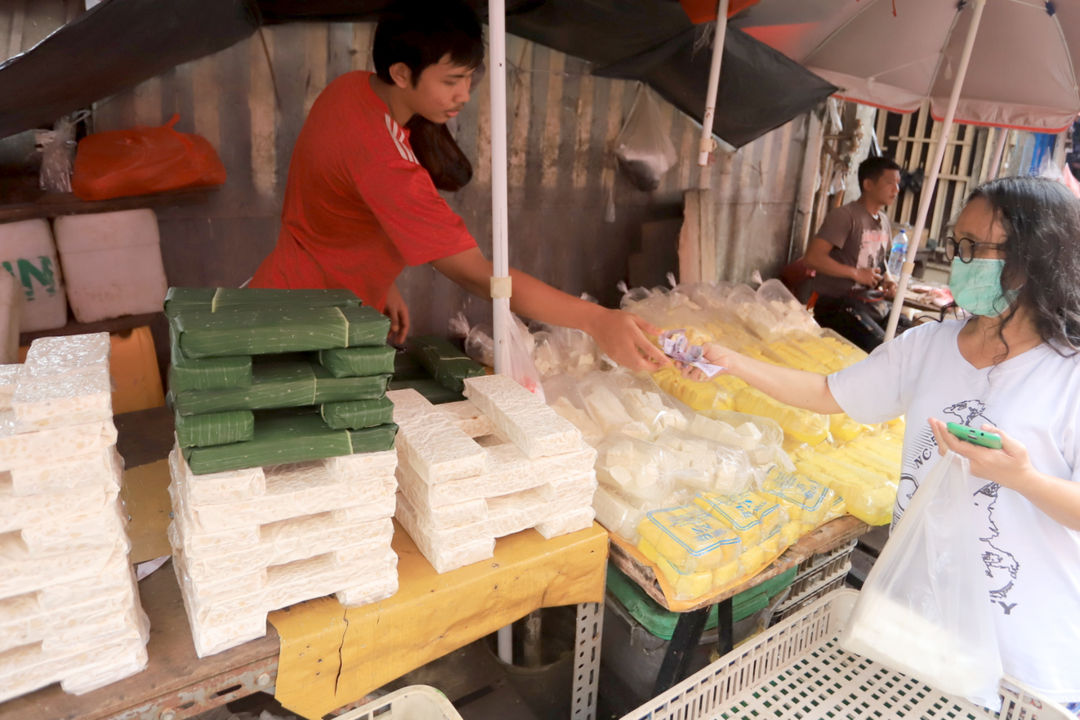 Pedagang tempe melayani pembeli di lapaknya di pasar kebayoran lama, Jakarta, Rabu, 16 Februari 2022. Foto: Ismail Pohan/TrenAsia