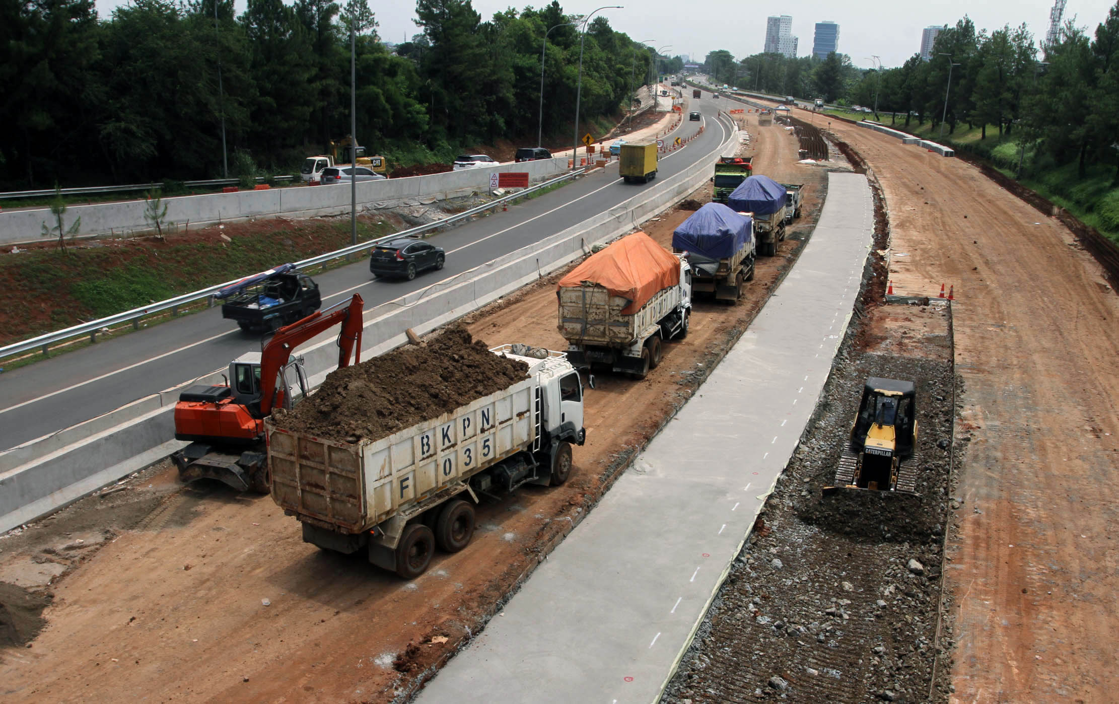 Nampak sejumlah pekerja menggunakan alat berat menyelesaikan pembangunan jalan tol Serpong - Balaraja (Serbaraja) di kawasan Rawa Buntu , Tangerang Selatan Selasa 8 Maret 2022. Foto : Panji Asmoro/TrenAsia