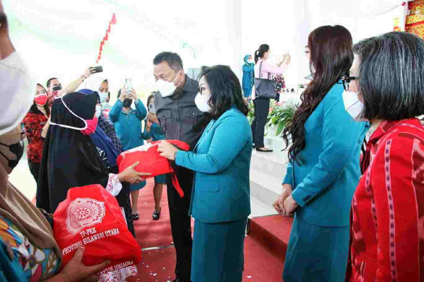 Ketua Tim Penggerak PKK Sulut, Rita Tamuntuan didampingi Gubernur Sulut Olly Dondokambey menyerahkan bantuan kepada warga di Bolmong. (Foto:Istimewa)