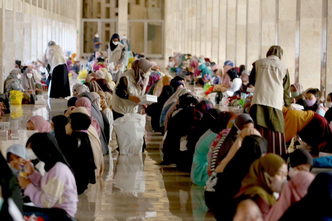 Panitia membagikan menu makanan kepada umat muslim yang mengikuti buka puasa bersama di aula Masjid Istiqlal, Jakarta, Selasa, 5 April 2022. Foto: Ismail Pohan/TrenAsia