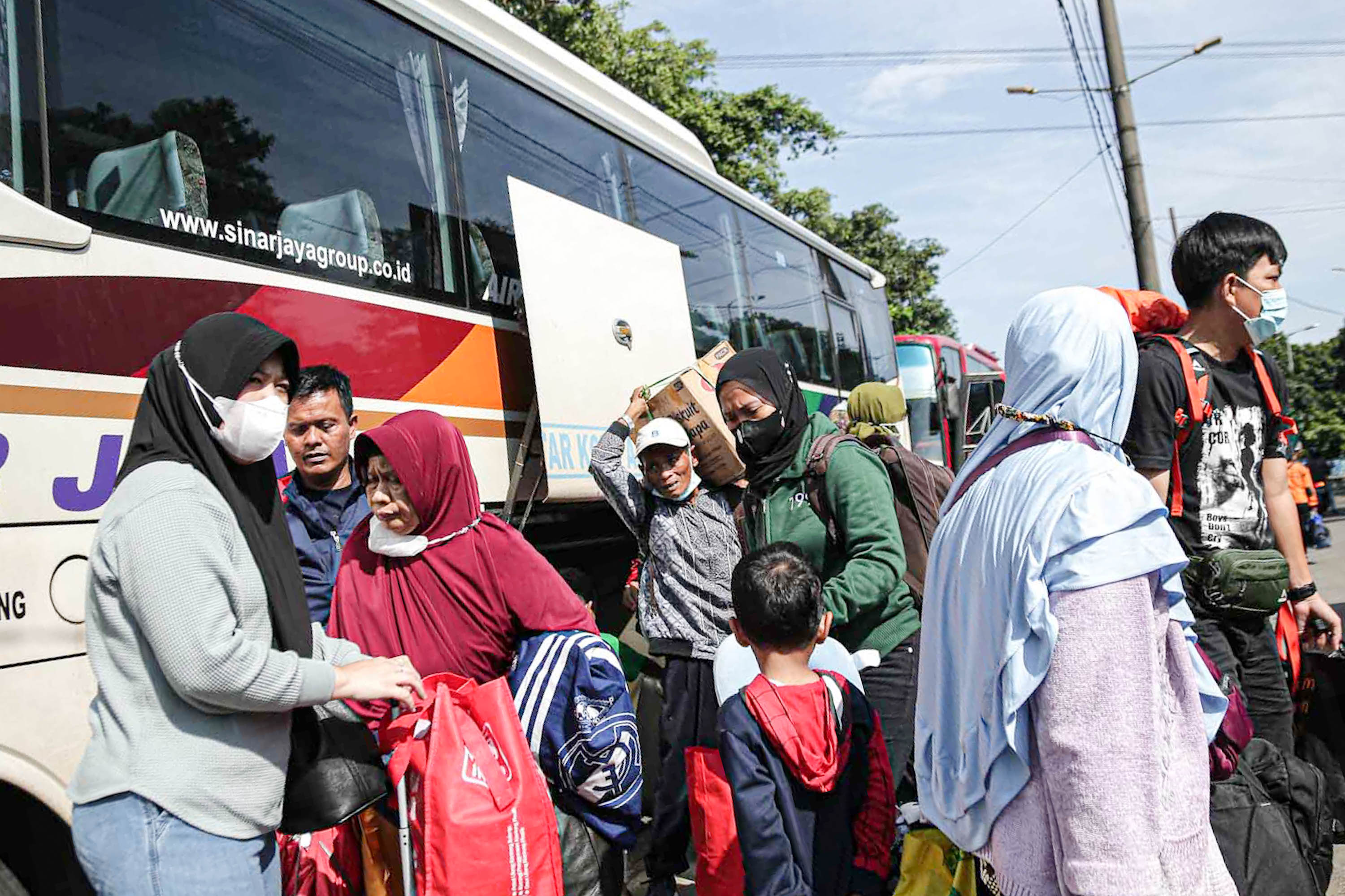 Pemudik membawa barang bawaannya setelah turun dari bus antarkota pada arus balik lebaran di Terminal Kampung Rambutan, Jakarta Timur, Minggu, 8 Mei 2022. Foto: Ismail Pohan/TrenAsia