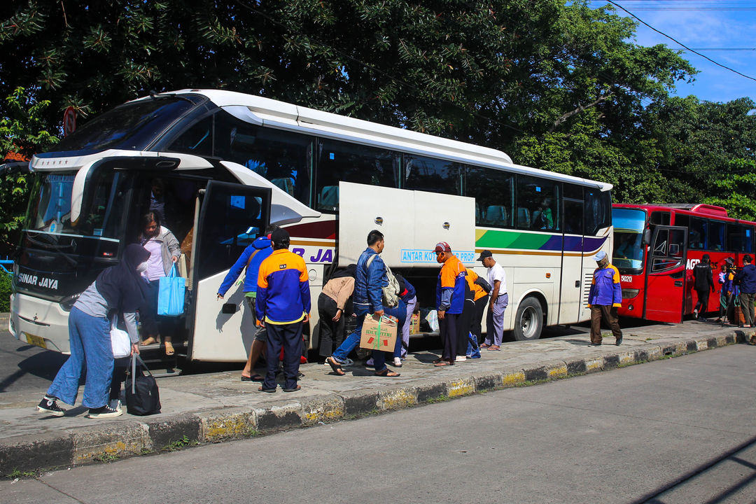 Pemudik membawa barang bawaannya setelah turun dari bus antarkota pada arus balik lebaran di Terminal Kampung Rambutan, Jakarta Timur, Minggu, 8 Mei 2022. Foto: Ismail Pohan/TrenAsia