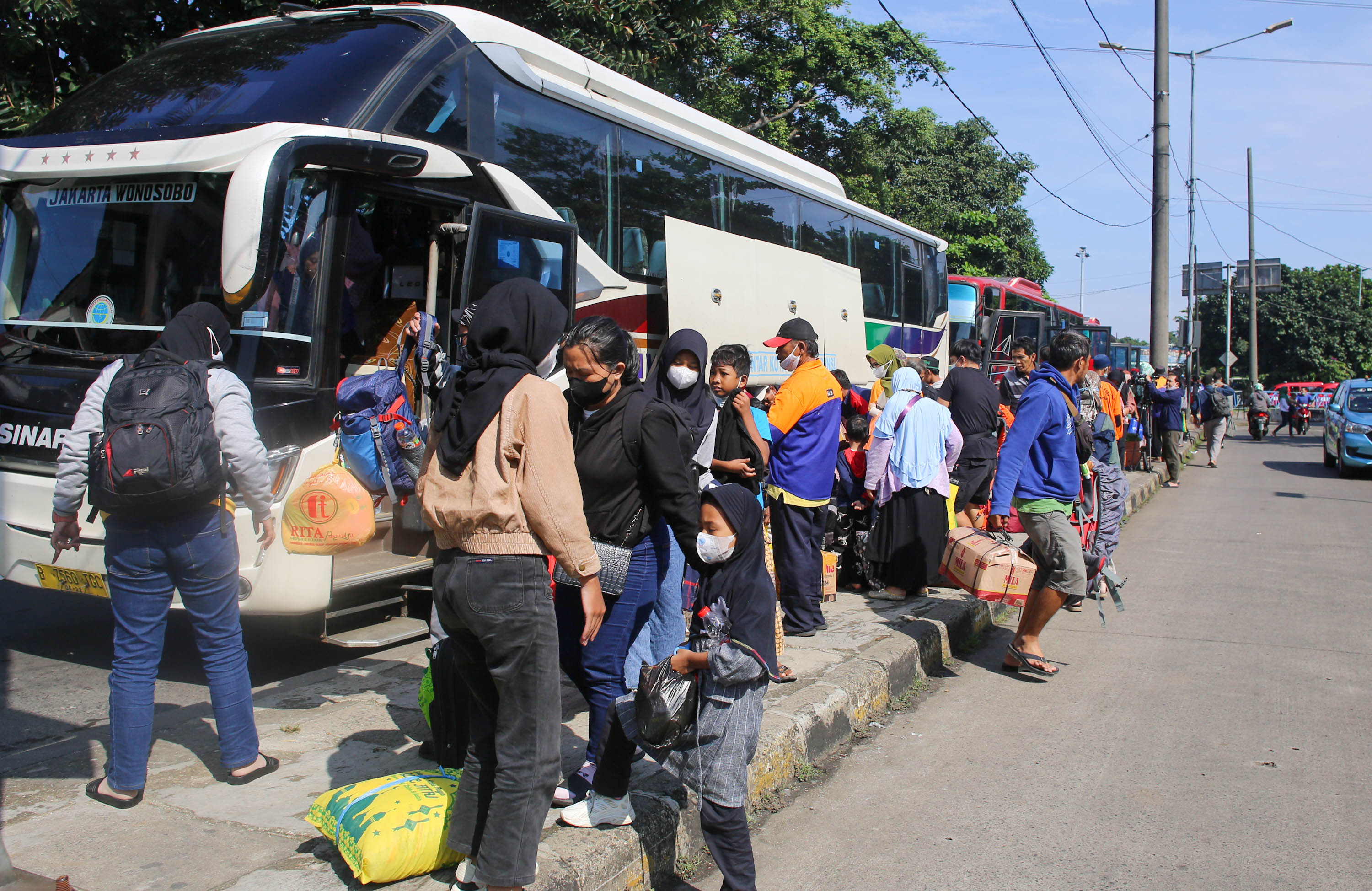 Pemudik membawa barang bawaannya setelah turun dari bus antarkota pada arus balik lebaran di Terminal Kampung Rambutan, Jakarta Timur, Minggu, 8 Mei 2022. Foto: Ismail Pohan/TrenAsia