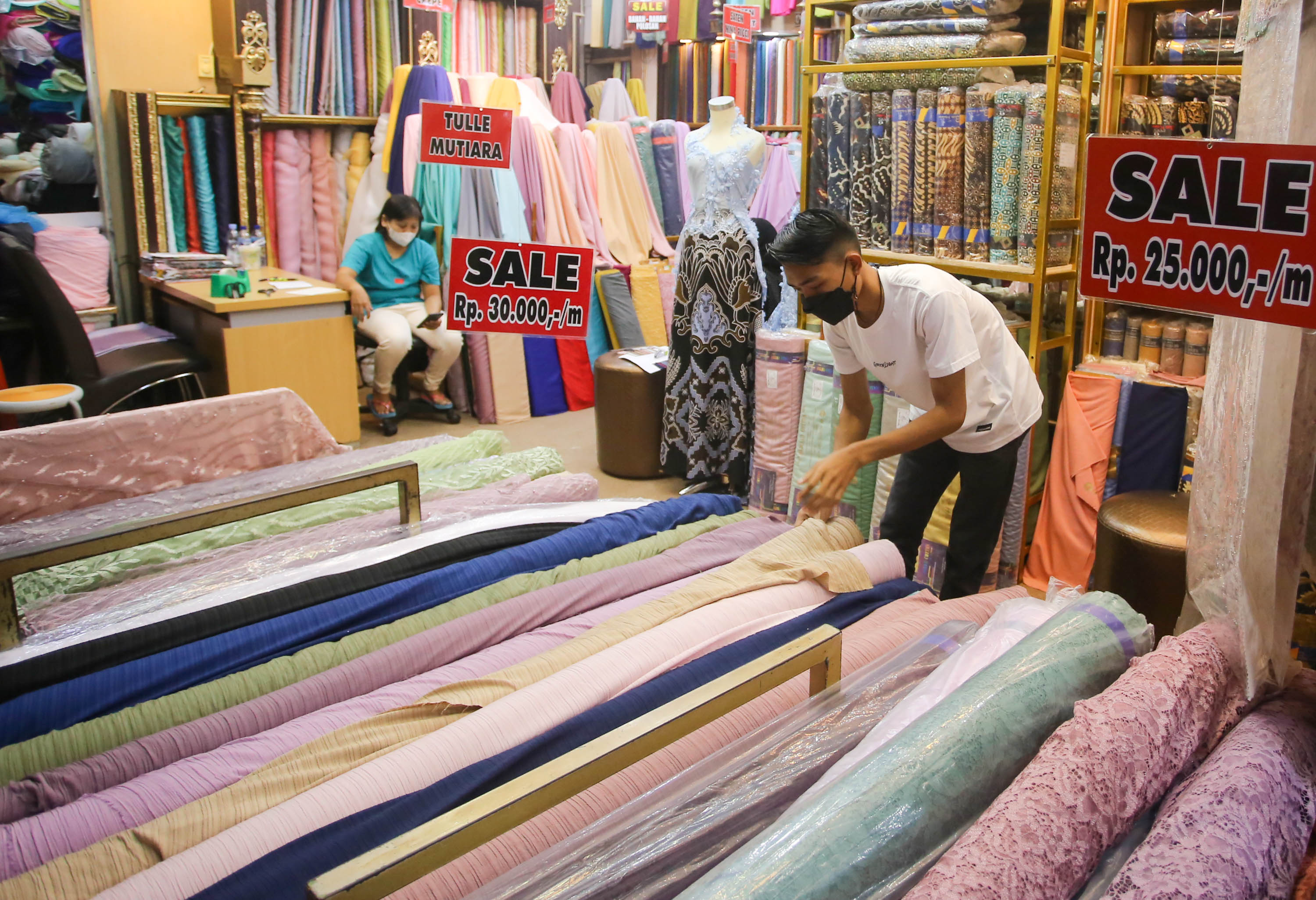Pedagang menata gulungan kain bahan di kiosnya pusat grosir tekstil Pasar Tanah Abang, Jakarta, Jum'at, 20 Mei 2022. Foto: Ismail Pohan/TrenAsia