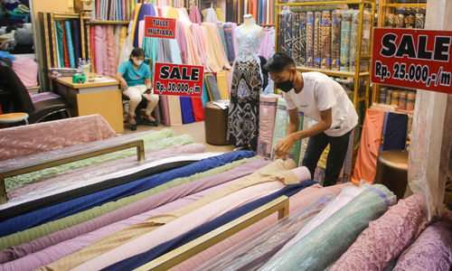 Pedagang menata gulungan kain bahan di kiosnya pusat grosir tekstil Pasar Tanah Abang, Jakarta, Jum'at, 20 Mei 2022. Foto: Ismail Pohan/TrenAsia