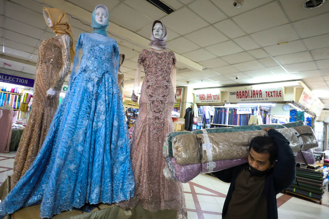 Pekerja mengangkat gulungan kain bahan di pusat grosir tekstil Pasar Tanah Abang, Jakarta, Jum'at, 20 Mei 2022. Foto: Ismail Pohan/TrenAsia