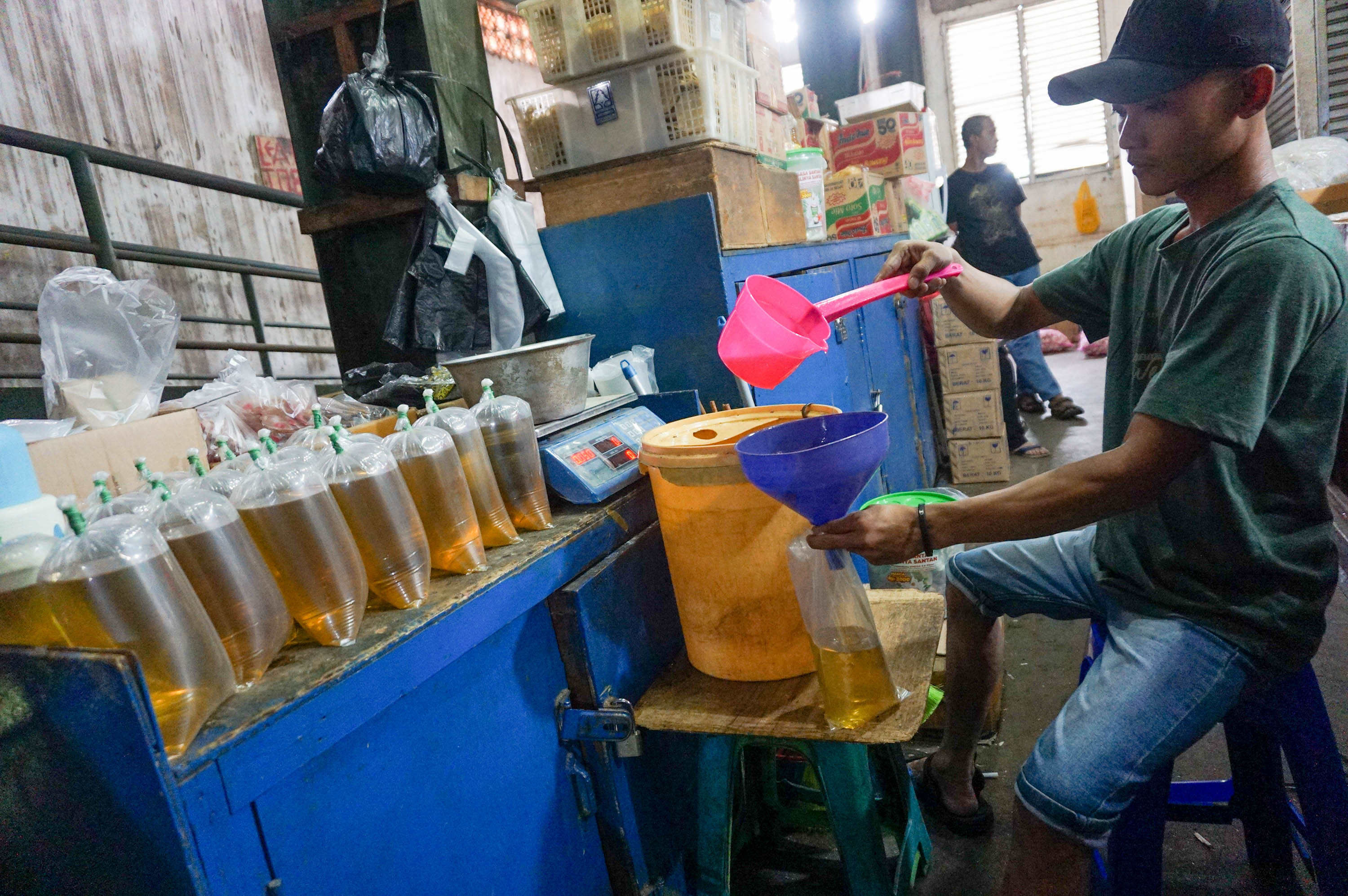 Pekerja mengemas minyak goreng curah di kios Pasar Senen, Jakarta. Foto: Ismail Pohan/TrenAsia