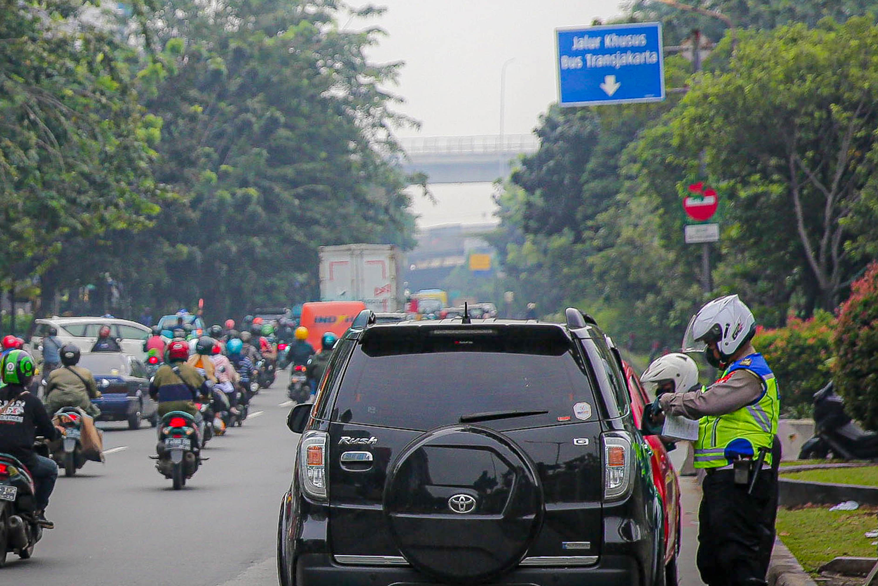 Petugas kepolisian melakukan penindakan kepada pengendara saat pemberlakuan perluasan kawasan ganjil genap di ruas jalan DI Panjaitan, Cawang, Jakarta, Senin, 6 Juni 2022. Foto: Ismail Pohan/TrenAsia