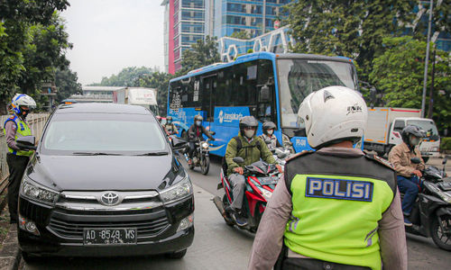 Petugas kepolisian berjaga saat pemberlakuan perluasan kawasan ganjil genap di ruas jalan DI Panjaitan, Cawang, Jakarta, Senin, 6 Juni 2022. Foto: Ismail Pohan/TrenAsia