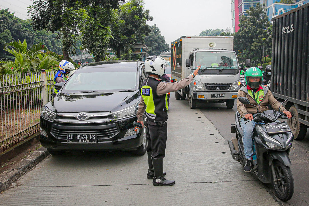 Petugas kepolisian berjaga saat pemberlakuan perluasan kawasan ganjil genap di ruas jalan DI Panjaitan, Cawang, Jakarta, Senin, 6 Juni 2022. Foto: Ismail Pohan/TrenAsia