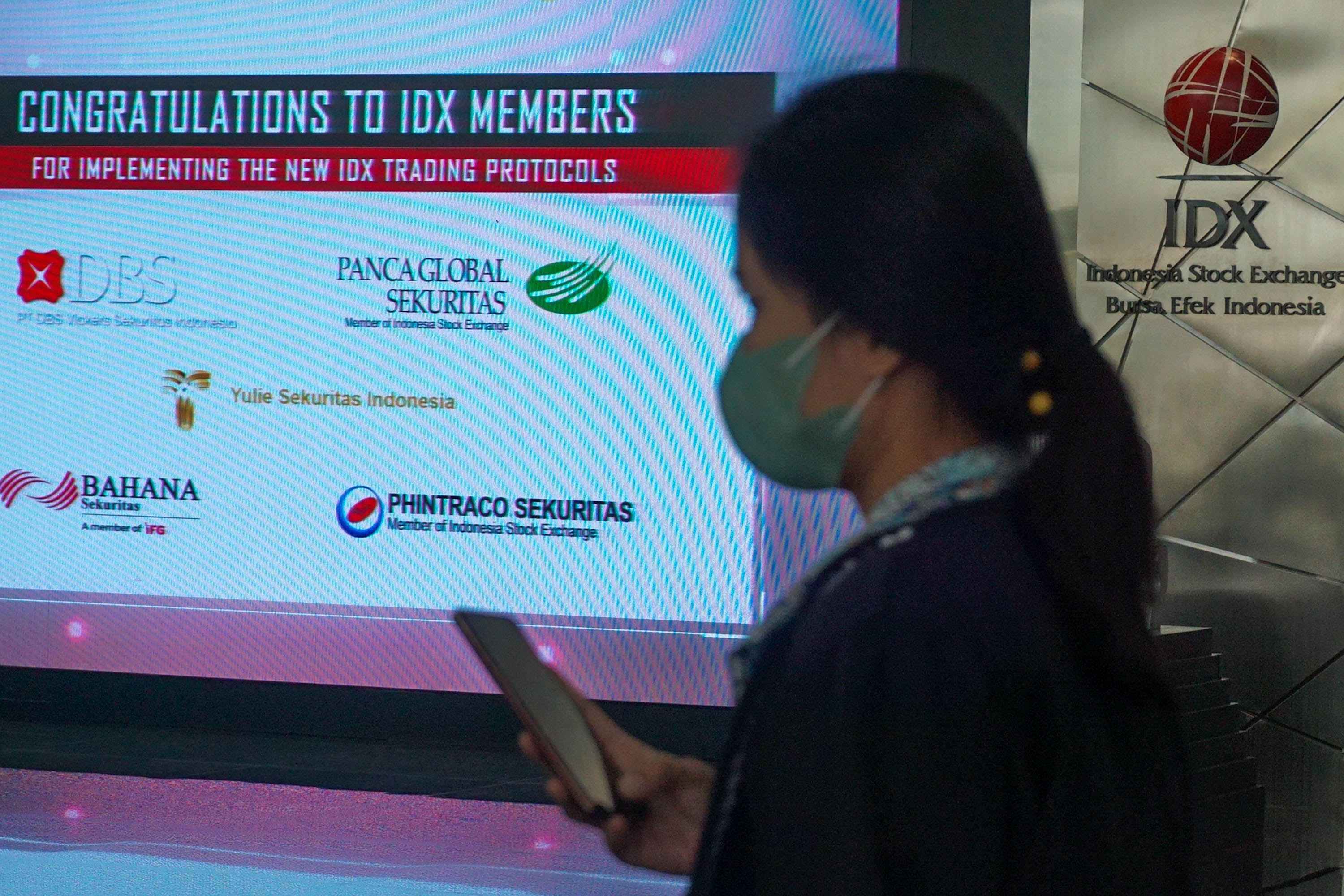 Karyawan melintas di dekat layar daftar perusahaan member IDX yang sudah melantai di Bursa Efek Indonesia (BEI), Jakarta,   Selasa, 7 Juni 2022. Foto: Ismail Pohan/TrenAsia