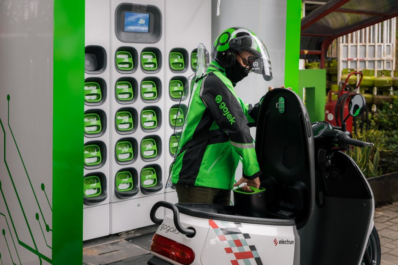 Seorang driver Gojek tengah melakukan pengisian baterai motor listriknya.
