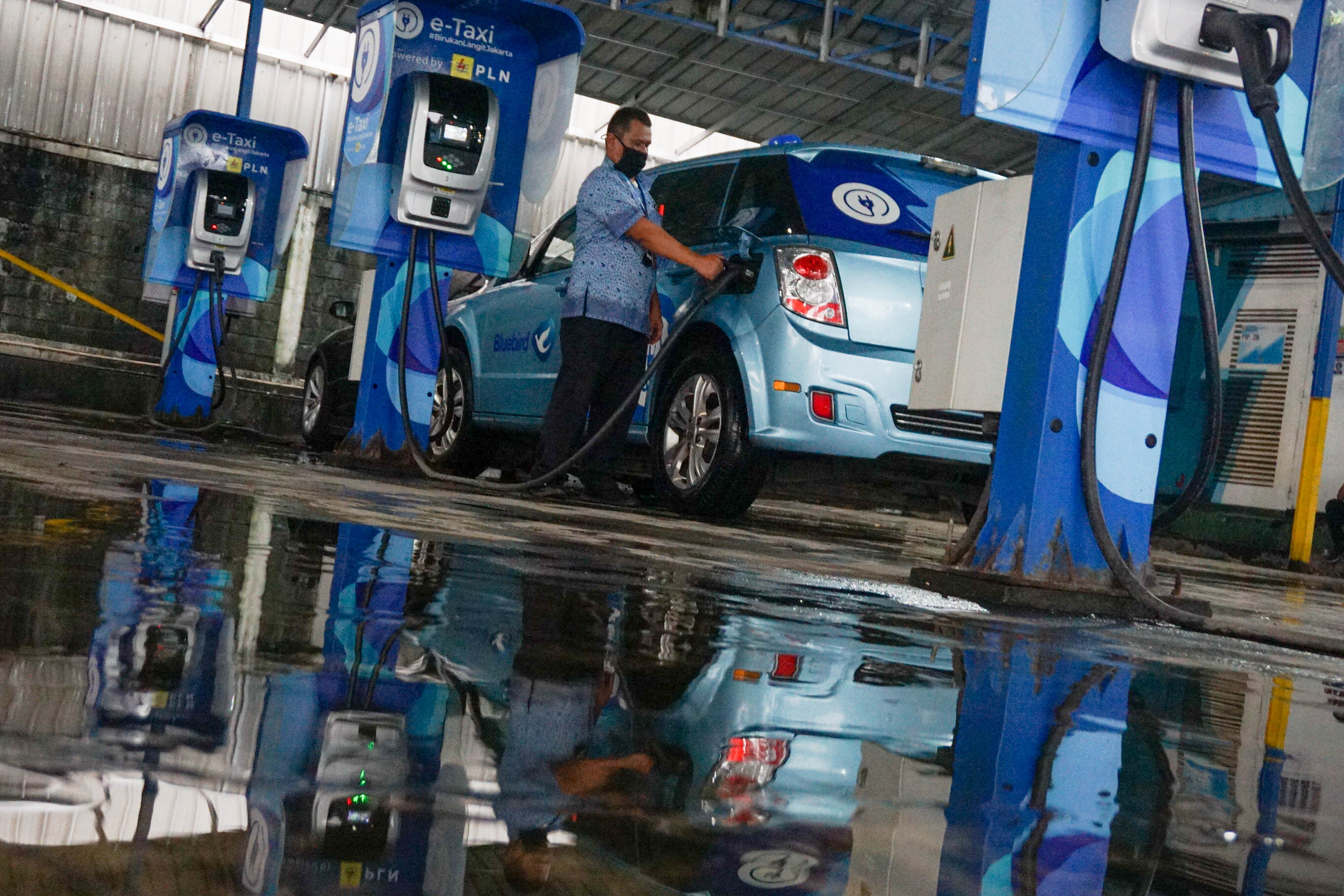 Pengemudi mengisi daya armada taksi listrik Bluebird (e-Taxi) di stasiun pengisian kendaraan listrik  Kantor Pusat Bluebird Group, Mampang Prapatan,  Jakarta, Rabu, 13 Juli 2022. Foto: Ismail Pohan/TrenAsia