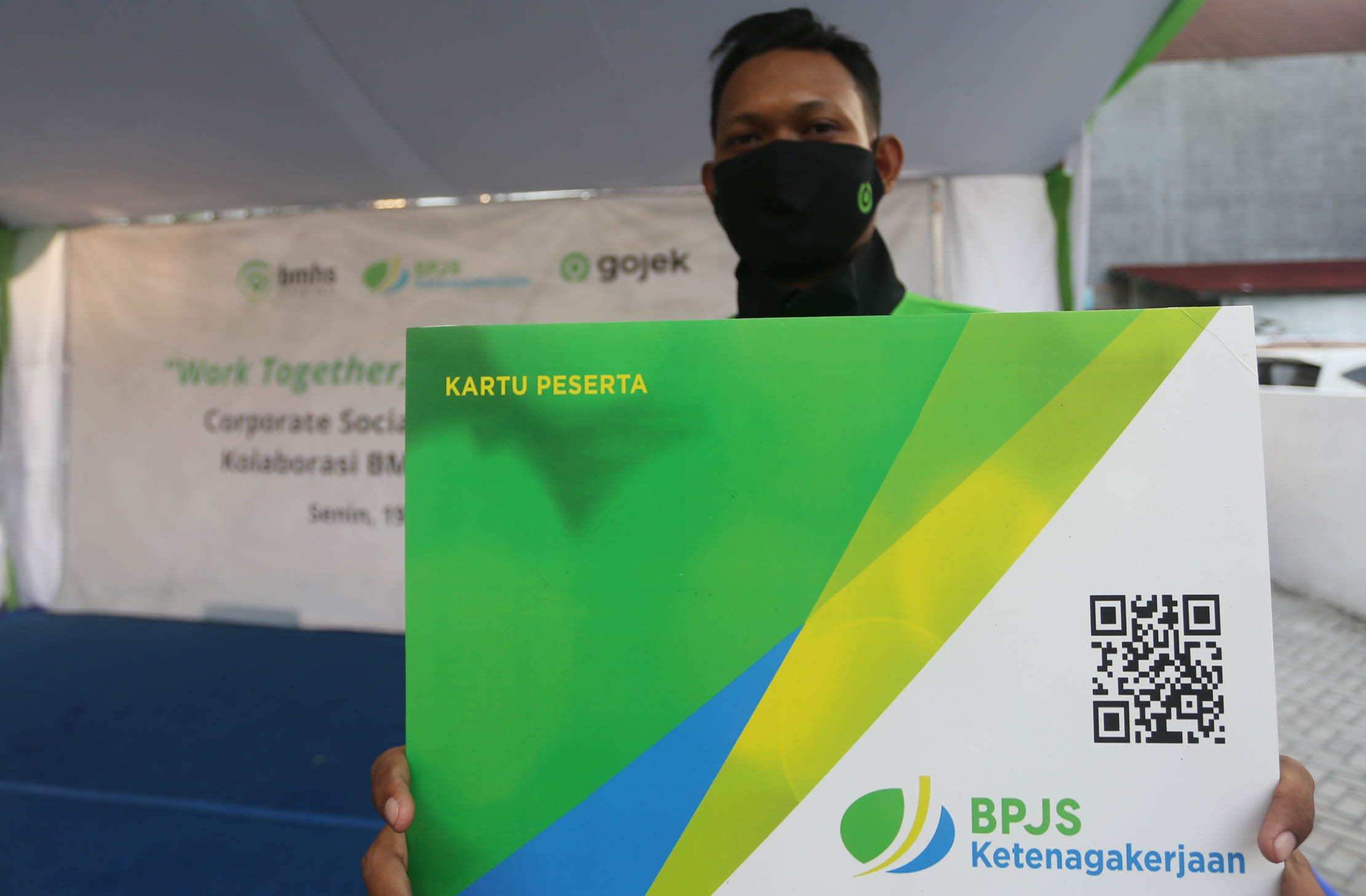 Perwakilan driver Gojek menunjukkan simbolis kartu BPJS usai penyerahan kartu perlindungan asuransi pada mitra pengemudi Gojek.Senin19 September 2022. Foto : Panji Asmoro/TrenAsia