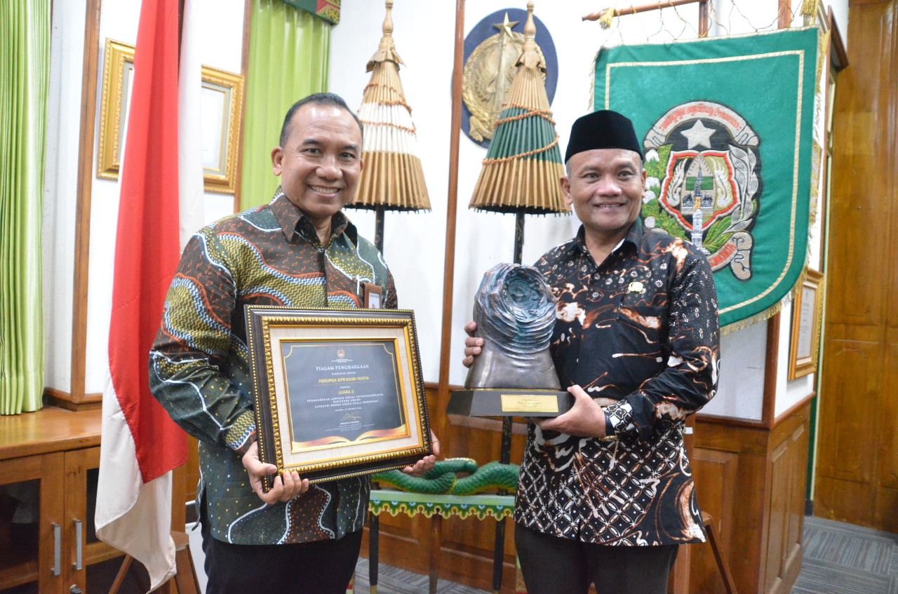 Direktur Utama Bank Jogja Kosim Junaedi menyerahkan penghargaan Paritrana Award 2022 kepada Penjabat Walikota Yogyakarta Sumadi.