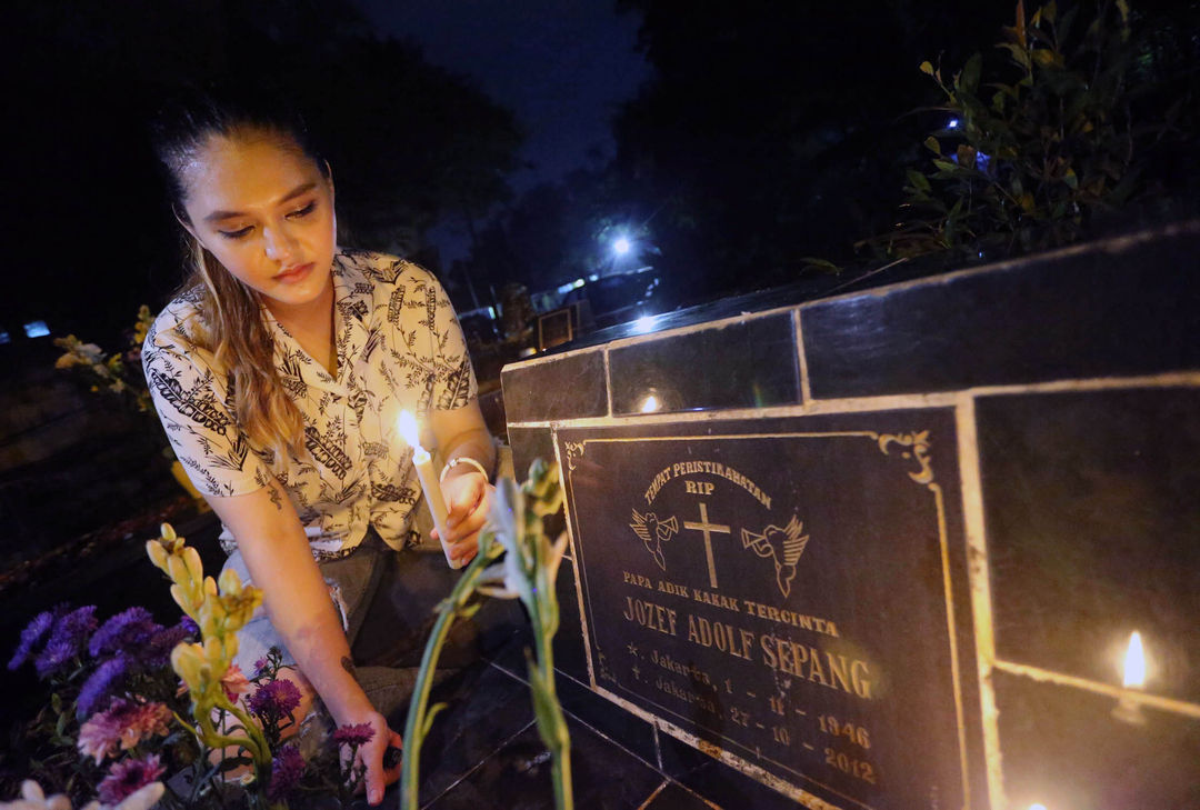 Sejumlah warga keturunan Portugis di Kampung Tugu Jakarta Utara melakukan tradisi ziarah malam Natal dimakam leluhur yang bersebelahan dengan Gereja Tugu, 24 Desember 2022. Foto : Panji Asmoro/TrenAsia