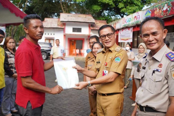 Bupati Minahasa Utara Joune Ganda menyerahkan secara simbolis sertifikat tanah kepada warga. (Foto:Istimewa)