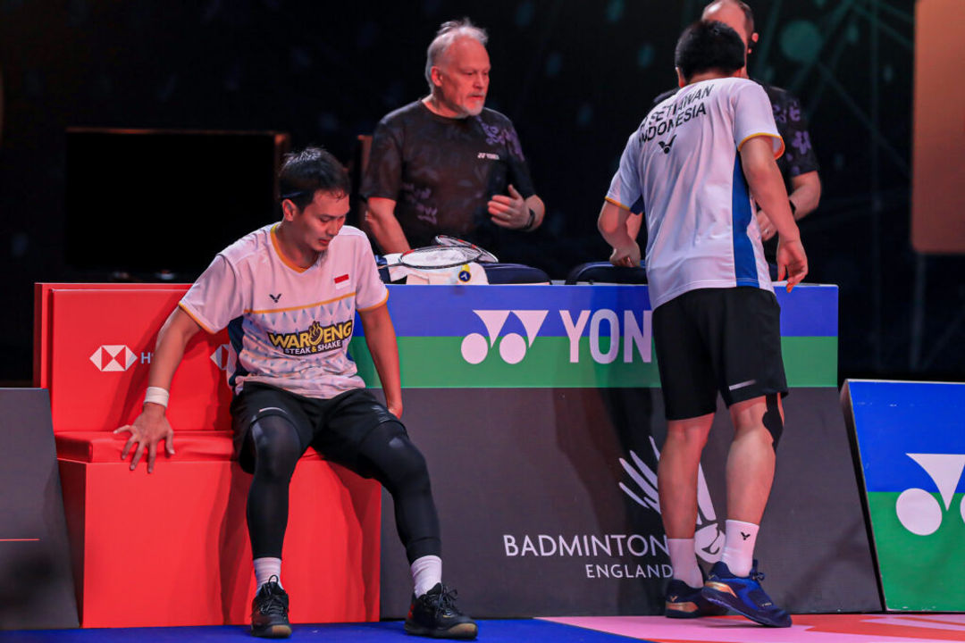 Mohammad Ahsan (kiri) menepi ke pinggir lapangan usai cedera dalam final All England 2023 di Birmingham, Minggu 19 Maret 2023 malam WIB.