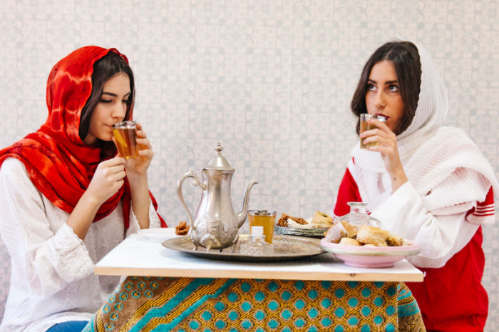 Ilustrasi dua wanita sedang menikmati hidangan lebaran
