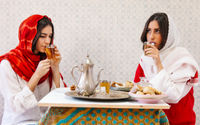 Ilustrasi dua wanita sedang menikmati hidangan lebaran
