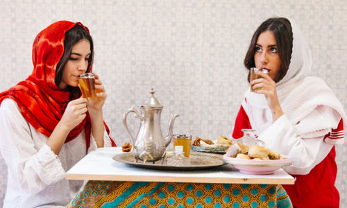Ilustrasi dua wanita sedang menikmati hidangan lebaran