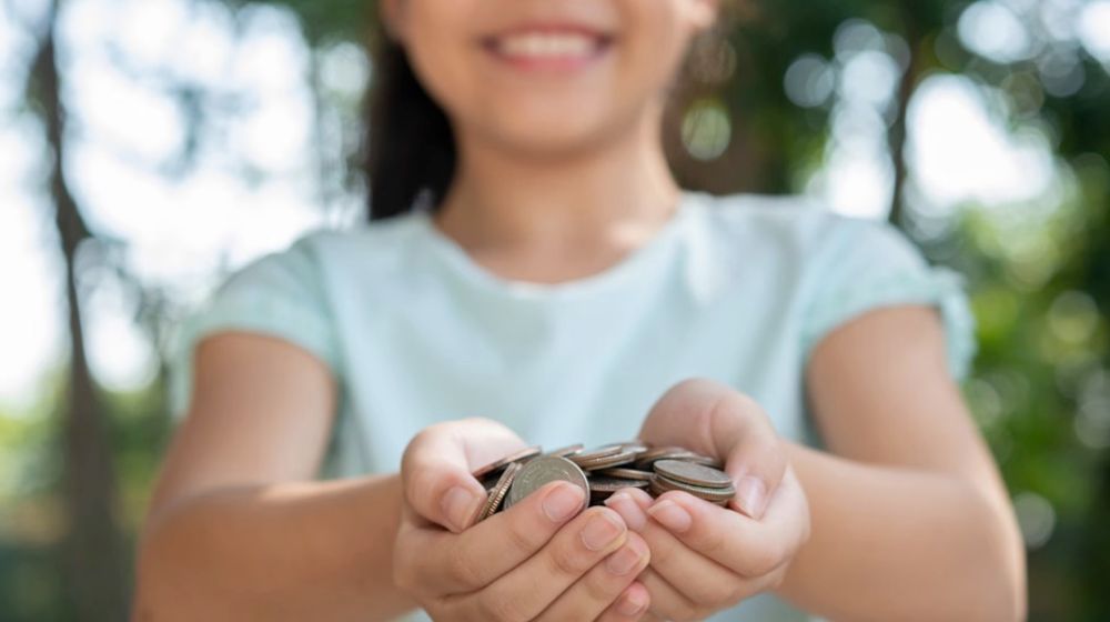 Ilustrasi anak menggenggam uang hasil tabungan.