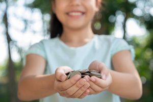 Ilustrasi anak menggenggam uang hasil tabungan.