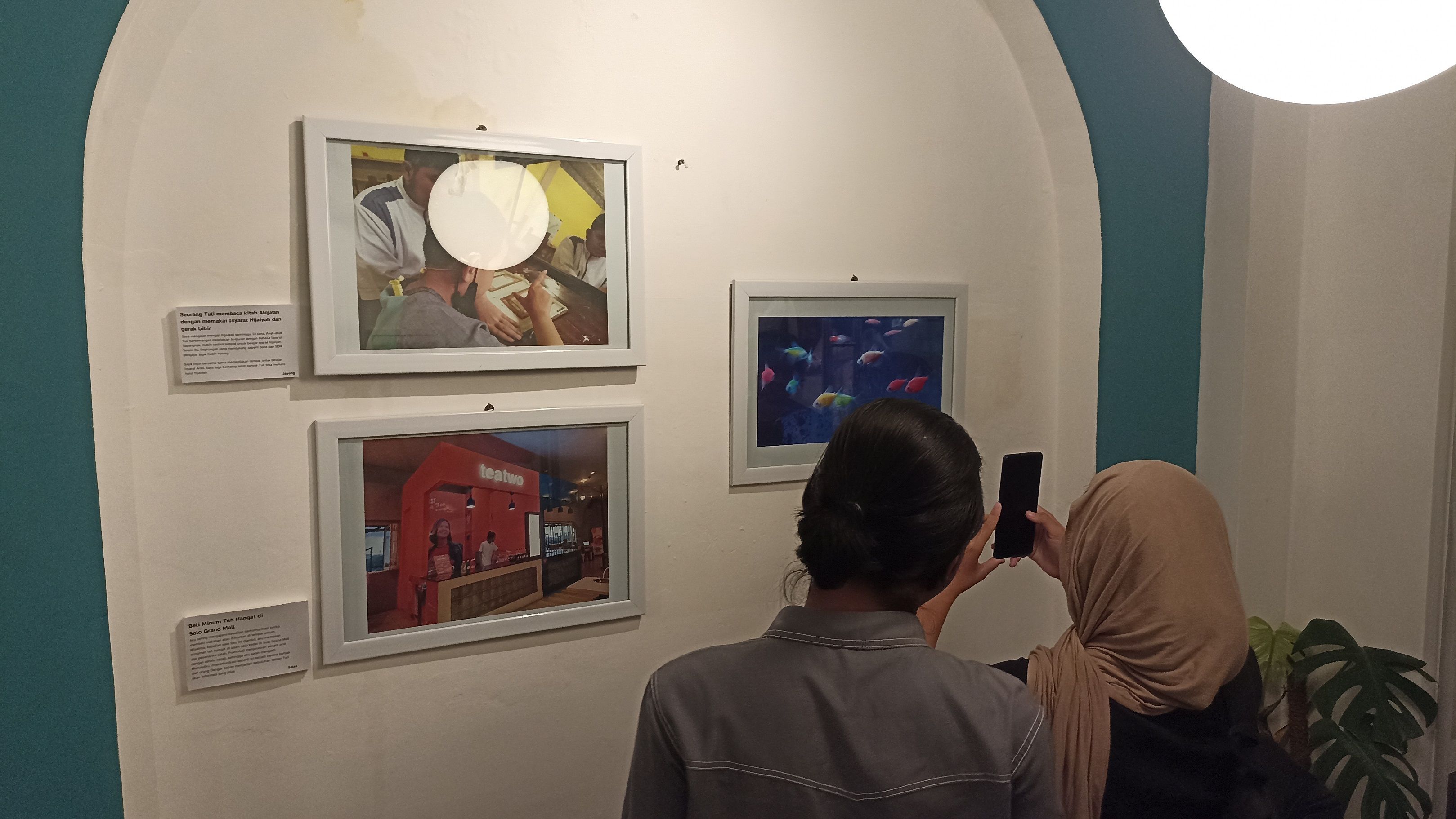Pengunjung menyaksikan deretan foto dalam pameran Teman Tuli Bercerita yang digelar di Nalla Coffee, Solo, Sabtu 27 Mei 2023 sore.