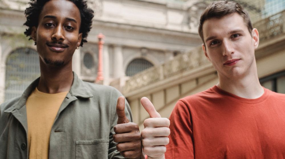 Photo by William Fortunato : https://www.pexels.com/photo/positive-young-multiracial-guys-demonstrating-thumbs-up-sign-at-camera-6140715/