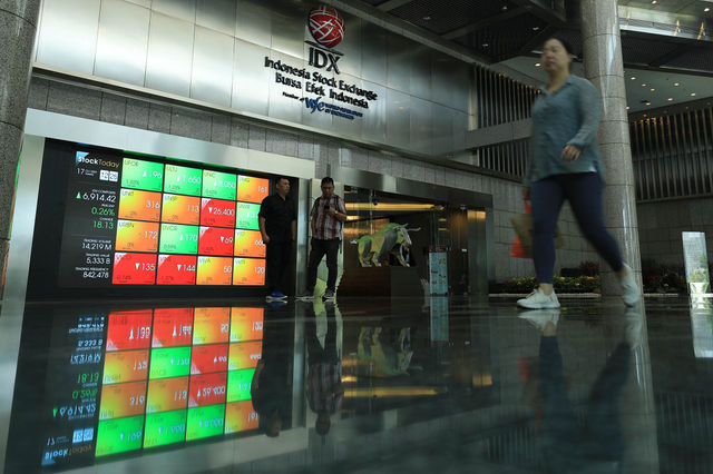 Pekerja berjalan di depan layar yang menampilkan pergerakan saham di Mail Hall Bursa Efek Indonesia (BEI), Jakarta 17 Oktober 2023. Foto : Panji Asmoro/TrenAsia