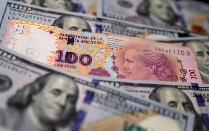Uang Kertas Seratus Peso Argentina Berada di Atas Beberapa Uang Kertas Seratus Dolar AS (Reuters/Agustin Markarian)