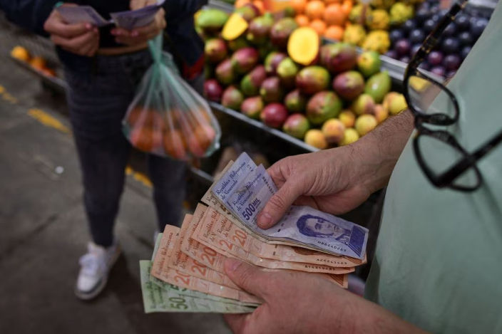 Seorang Pelanggan Menghitung Uang Kertas Bolivar Venezuela di Sebuah Kios di Pasar Kota di Caracas (Reuters/Gaby Oraa)