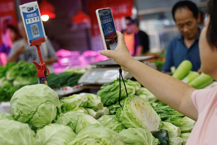 Seorang Pelanggan Memindai Kode QR untuk Membayar Sayuran di Pasar, Beijing (Reuters/Tingshu Wang)