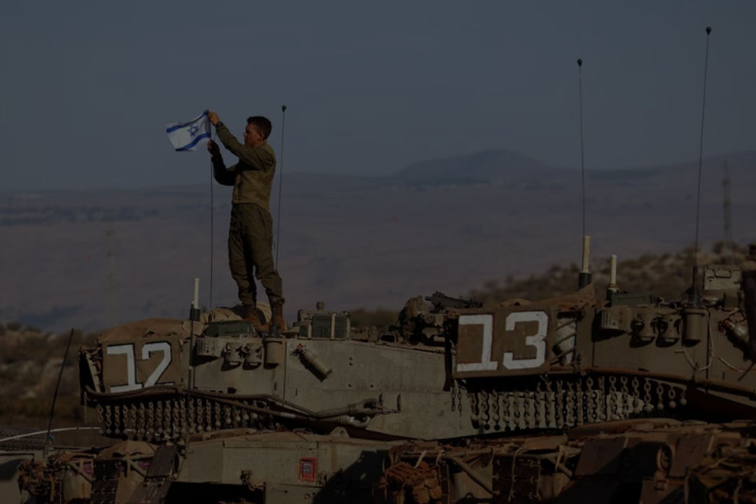 Seorang Tentara Memasang Bendera Israel di Sebuah Tank Selama Latihan Militer di Dekat Perbatasan Israel (Reuters/Lisi Niesner)