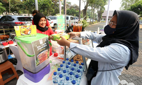 Erfianty Owner Ayam Bakar Madu Hijrah (kiri) Jagakarsa, salah satu UMKM yang mendapatkan manfaat pendanaan dari OVO Finansial melayani pelanggan saat bazaar di Universitas Pancasila, Jakarta, Senin 30 Oktober 2023. Foto : Panji Asmoro/TrenAsia