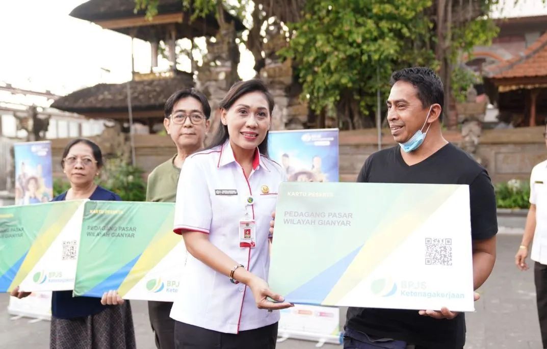 Kepala Dinas Tenaga Kerja Ida Ayu Surya Adnyani menyerahkan secara simbolik kartu BPJAMSOSTEK ke pedagang di Pasar Ubud, Gianyar. 