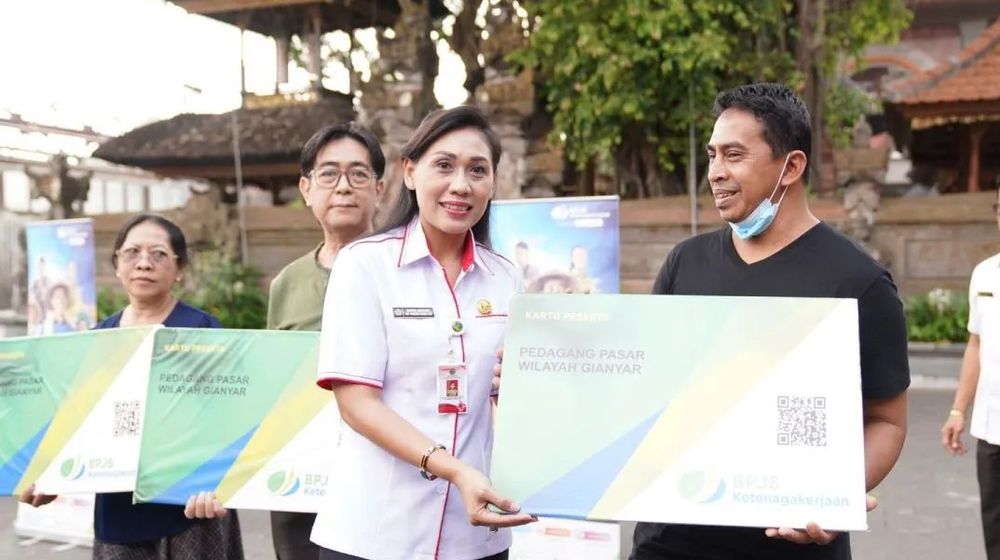 Kepala Dinas Tenaga Kerja Ida Ayu Surya Adnyani menyerahkan secara simbolik kartu BPJAMSOSTEK ke pedagang di Pasar Ubud, Gianyar. 