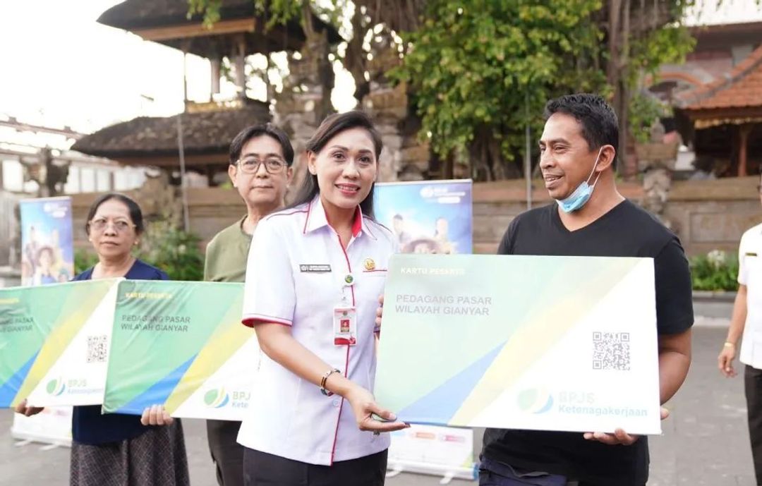 Kepala Dinas Tenaga Kerja Ida Ayu Surya Adnyani menyerahkan secara simbolik kartu BPJAMSOSTEK ke pedagang di Pasar Ubud, Gianyar. 