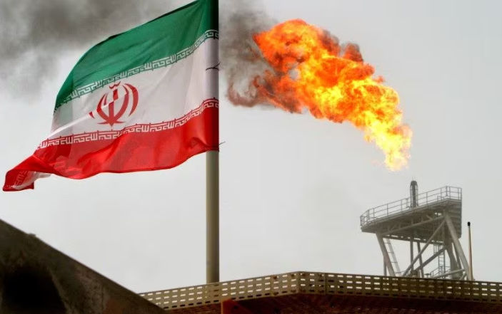 Sebuah Suar Gas di Anjungan Produksi Minyak Terlihat di Samping Bendera Iran (Reuters/Raheb Homavandi)