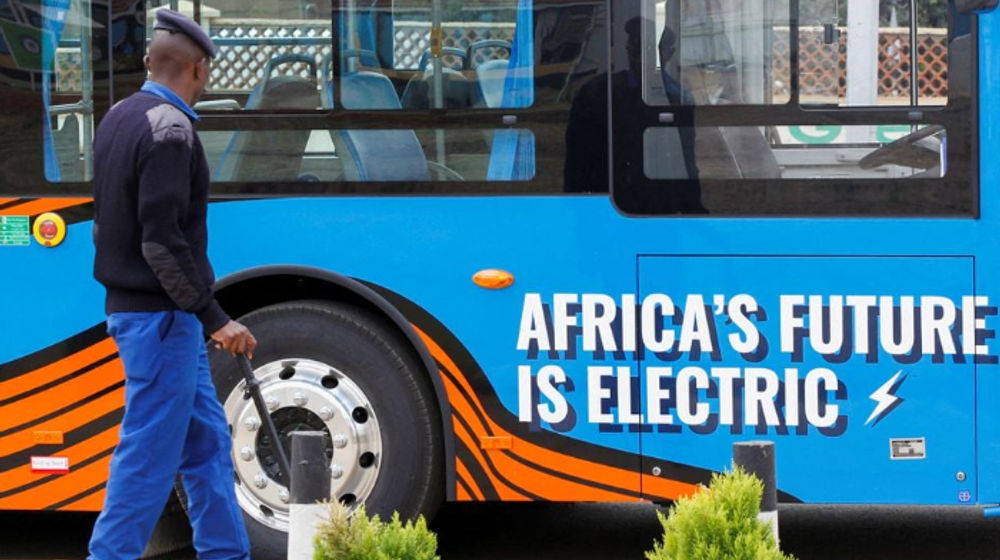 Seorang Petugas Polisi Berjalan di Samping Bus Angkutan Massal Listrik yang Dirakit oleh Ruang Produsen Kendaraan istrik di Terminal Green Park di Nairobi