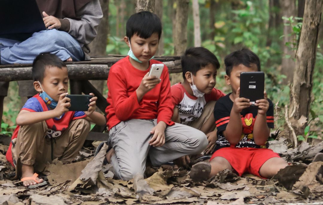 Anak-Anak yang bermain handphone dalam mengakses ruang digital