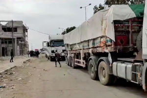 Orang-Orang Berjalan di Samping Truk dengan Bantuan Kemanusiaan yang Dikirimkan oleh Masyarakat Bulan Sabit Merah Palestina, menuju Gaza Utara