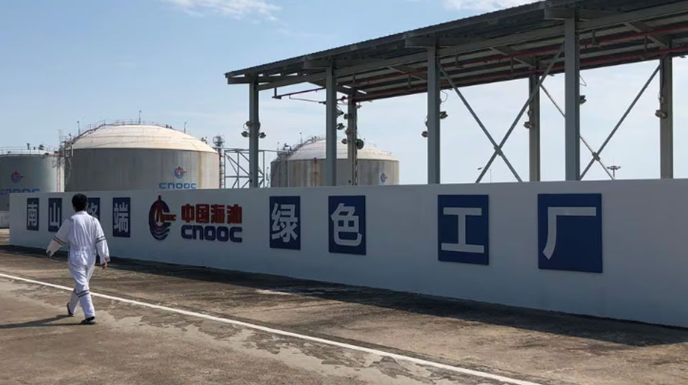 Seorang Pekerja Berjalan Melewati Logo Perusahaan Minyak Lepas Pantai Nasional China (CNOOC) di Terminal Gas Alam Cair (LNG) Nanshan di provinsi Hainan, China