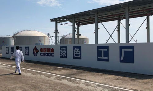 Seorang Pekerja Berjalan Melewati Logo Perusahaan Minyak Lepas Pantai Nasional China (CNOOC) di Terminal Gas Alam Cair (LNG) Nanshan di provinsi Hainan, China